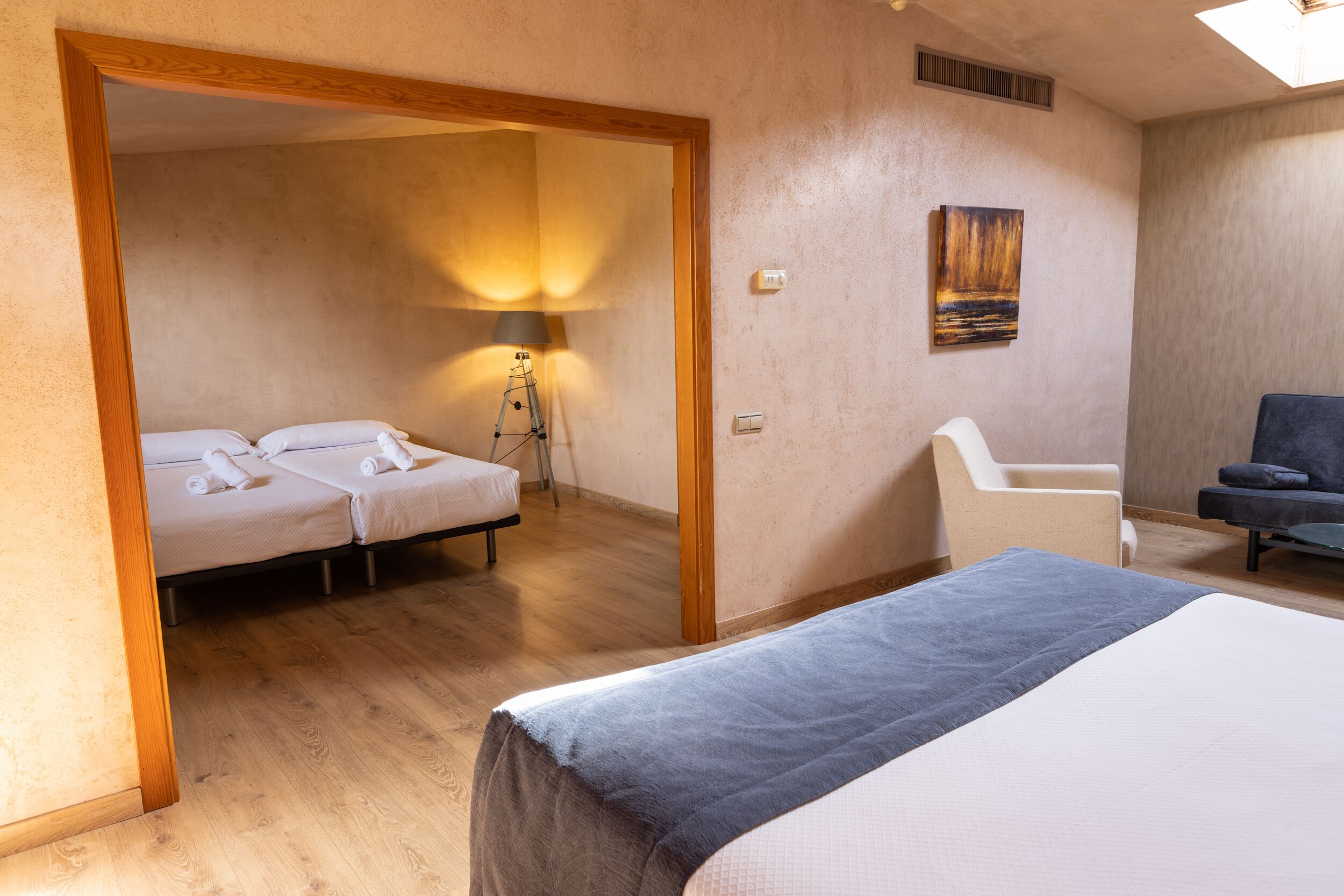 Una habitación de hotel con dos camas, un escritorio, una silla y una lámpara.