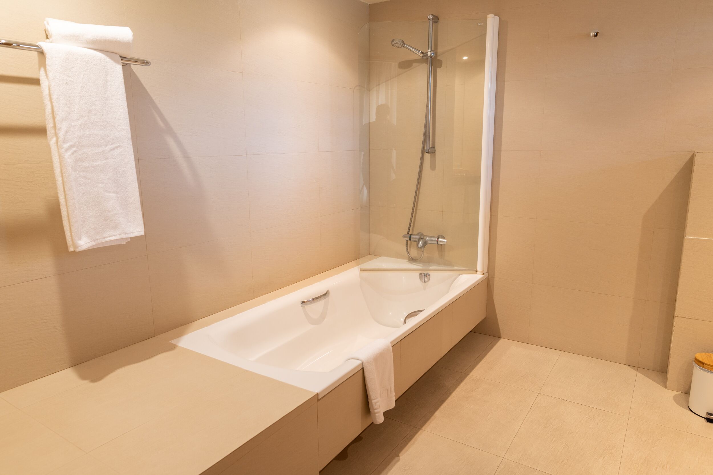 Un baño moderno con bañera, ducha con mampara de vidrio y un inodoro.