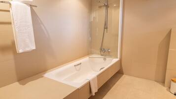 Un baño moderno con bañera, ducha con mampara de vidrio y un inodoro.