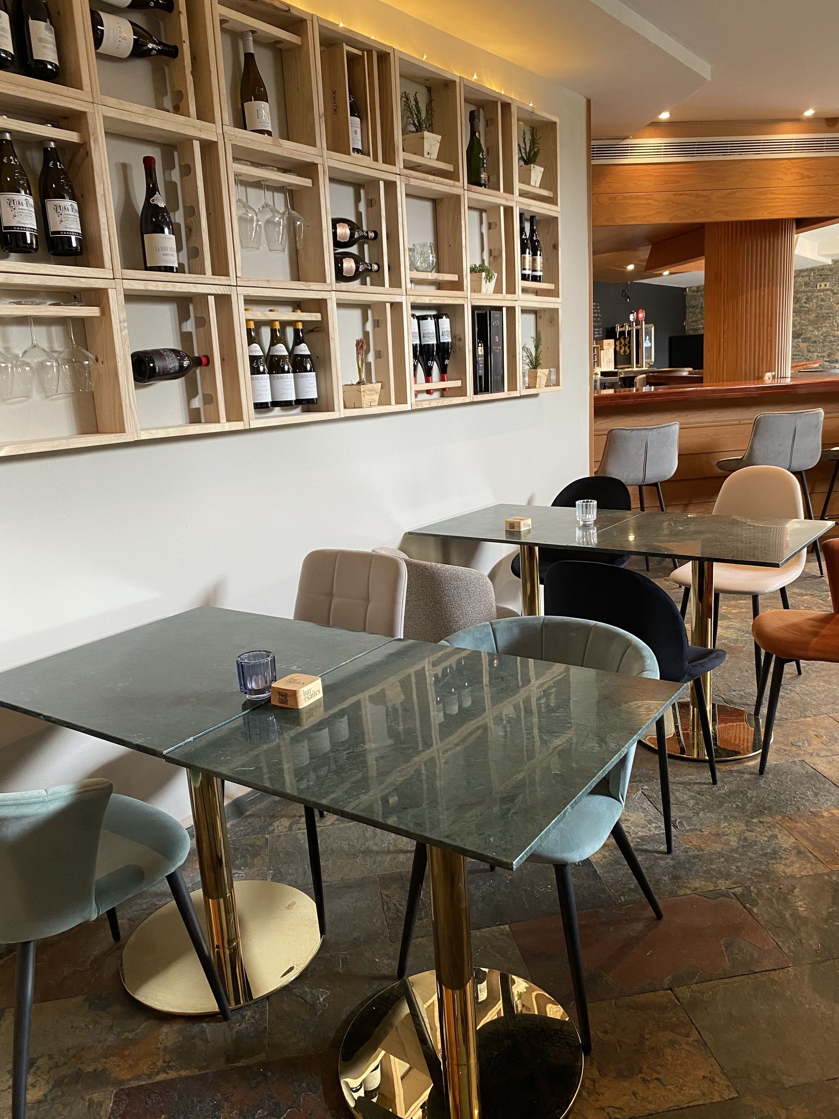 Un restaurante con una pared de exhibición de vinos, mesas de vidrio y sillas modernas.