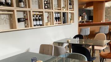 Un restaurante con una pared de exhibición de vinos, mesas de vidrio y sillas modernas.