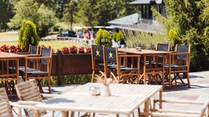 Outdoor wooden tables and chairs with black cushions and star designs, arranged on a stone patio. - Hotel Xalet del Golf (Bolvir)
