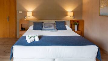 Un lit bien fait, recouvert d’une couvre-lit bleue et blanche, avec deux oreillers et un vase de fleurs posé sur la table de chevet.