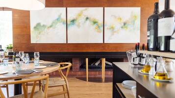 Un comedor moderno con chimenea de ladrillo, mobiliario de madera y arte abstracto en la pared.