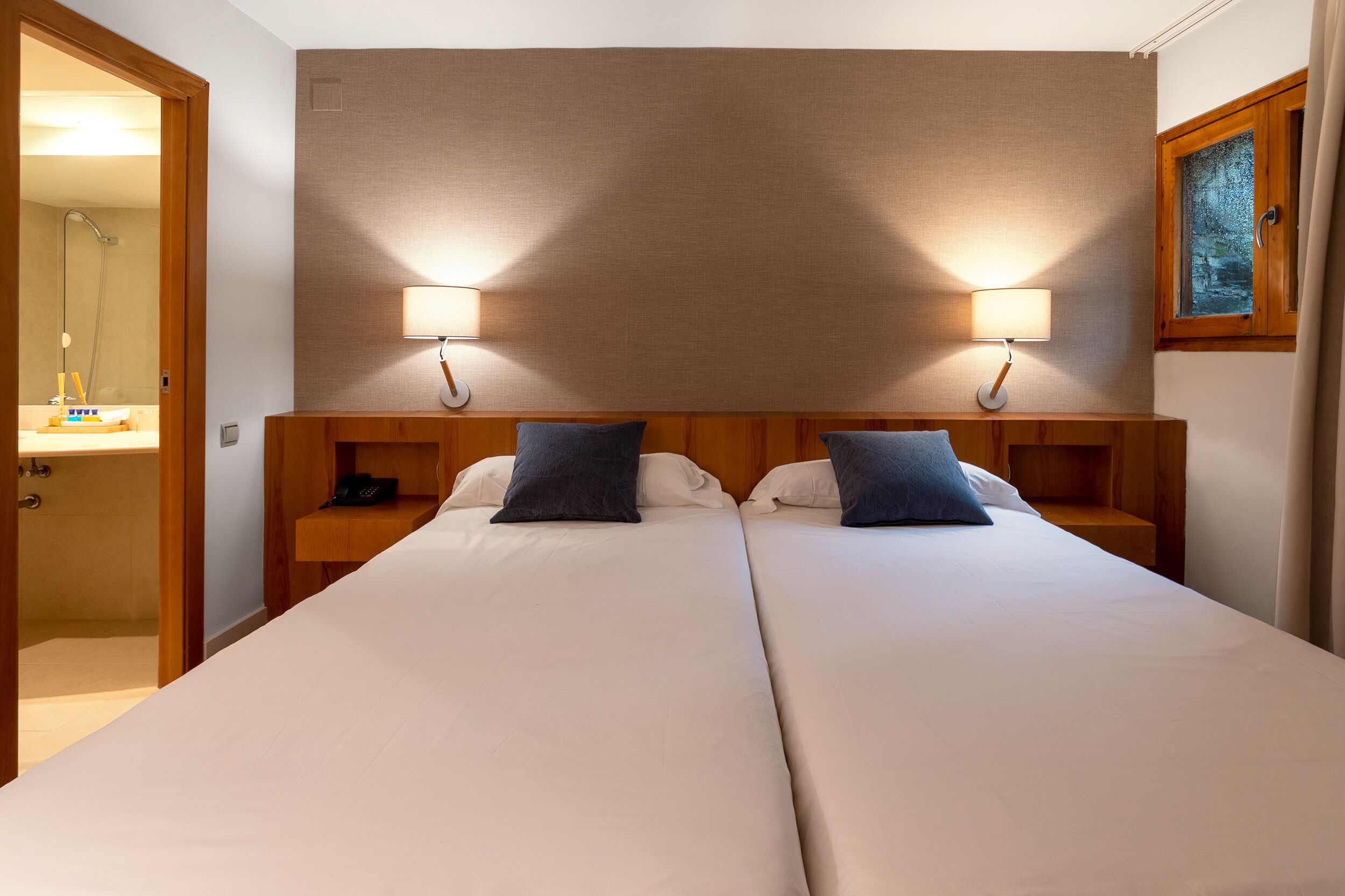 A double bed with two bedside tables, each with a lamp and a phone.