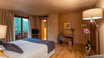A hotel room with a bed, desk, chair, and a lamp.