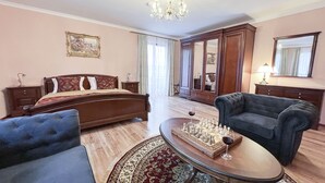 A bedroom with a bed, a sitting area with a coffee table, and a large mirror.