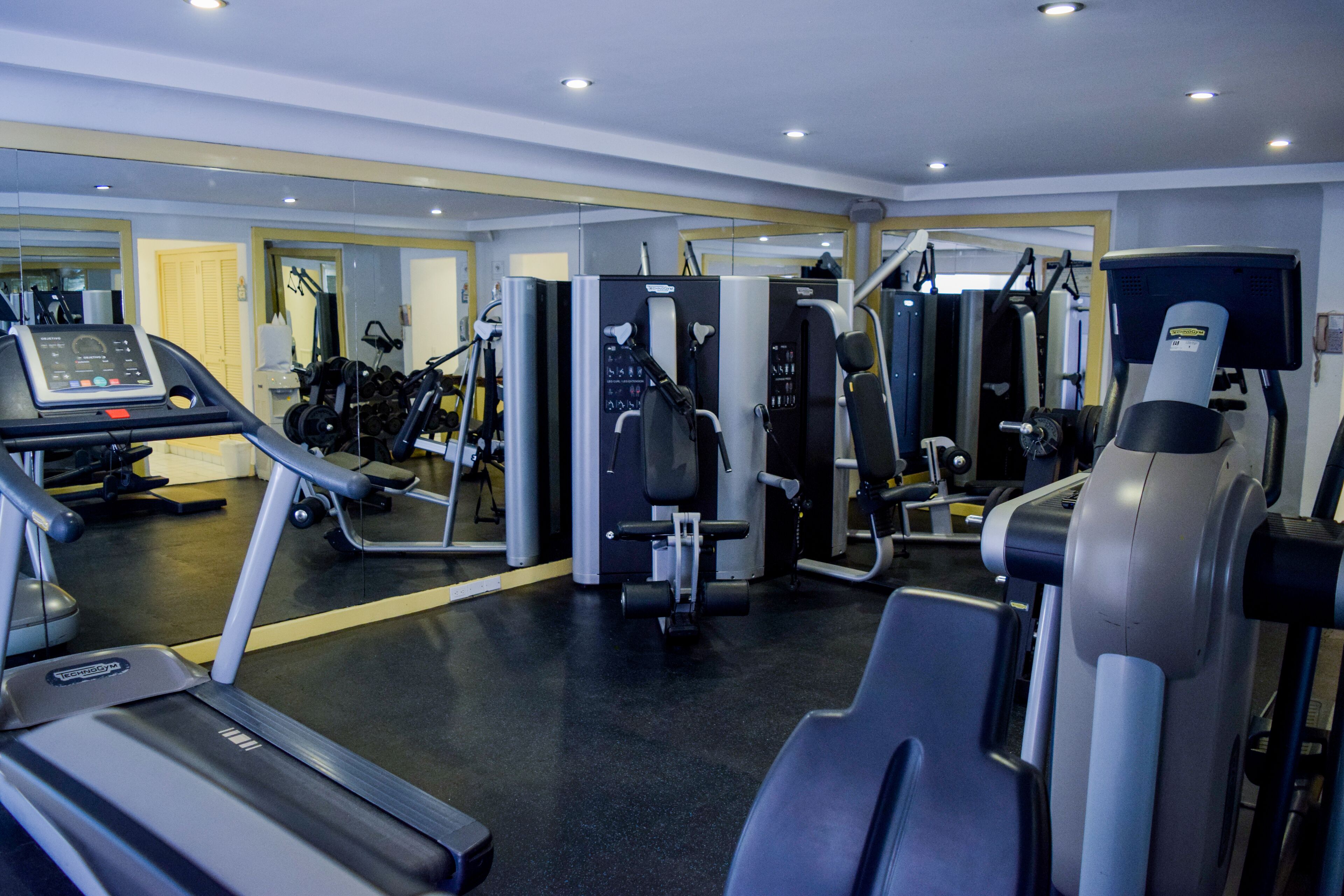 A gym with cardio machines, weightlifting equipment, and mirrors.