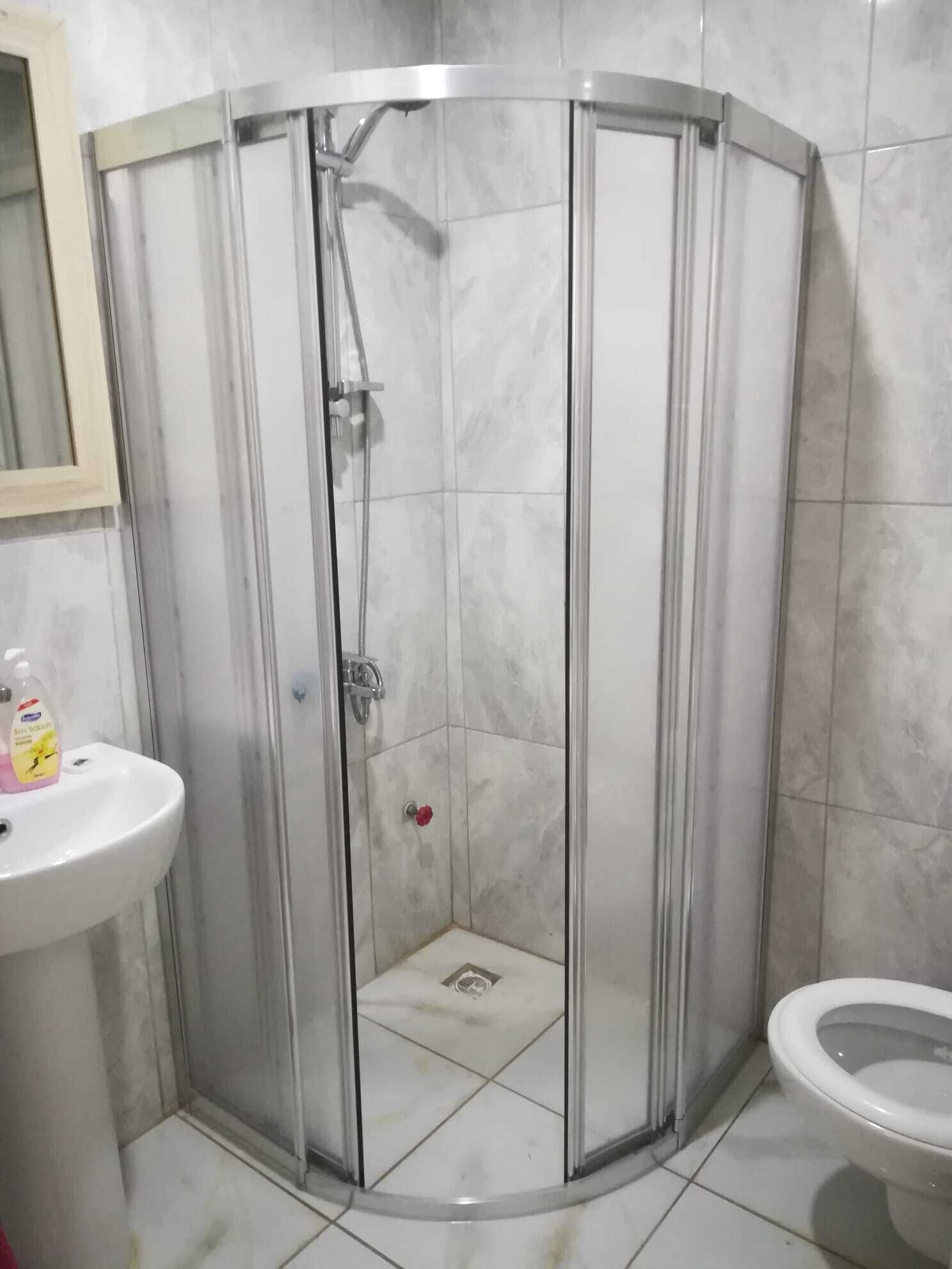 Een douchehoek met een glazen deur, een wit wastafelmeubel en een toilet.