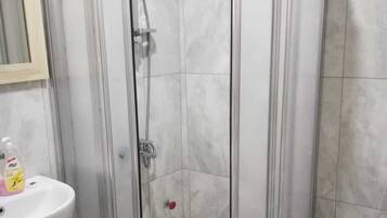 Een douchehoek met een glazen deur, een wit wastafelmeubel en een toilet.