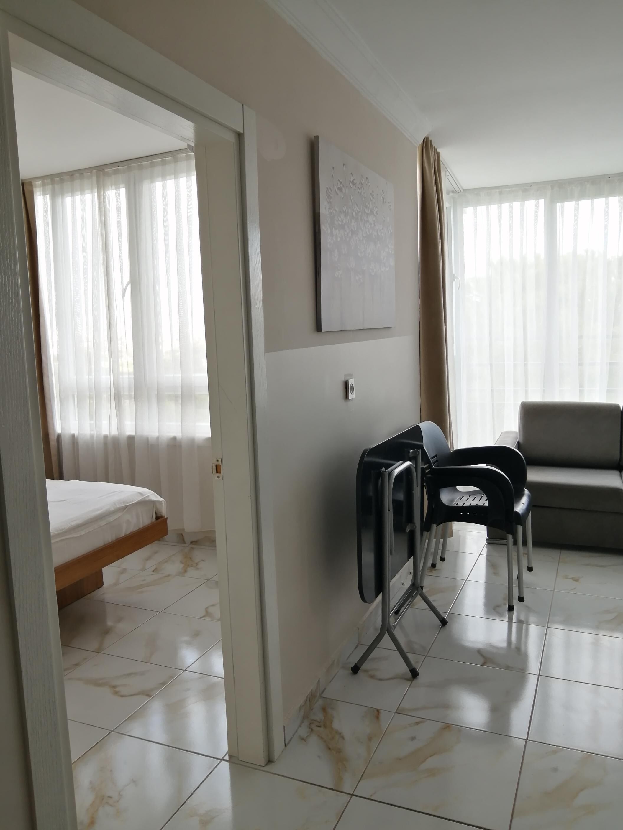Een hotelkamer met een bed, een bureau met stoelen, een bank en een schilderij aan de muur.