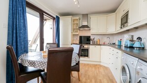 Eine kompakte Küche mit Essbereich, ausgestattet mit einer Waschmaschine, Mikrowelle und einem kleinen Backofen.