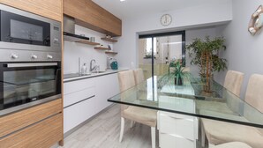 A modern kitchen with a built-in microwave, oven, and wooden cabinets. - Ophyris Apartment, Praia da Rocha, WiFi, AC !New! (Portimão)