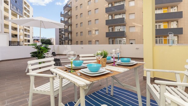 A rooftop terrace with a dining table set for four, surrounded by white chairs, and a large umbrella providing shade. - Ophyris Apartment, Praia da Rocha, WiFi, AC !New! (Portimão)