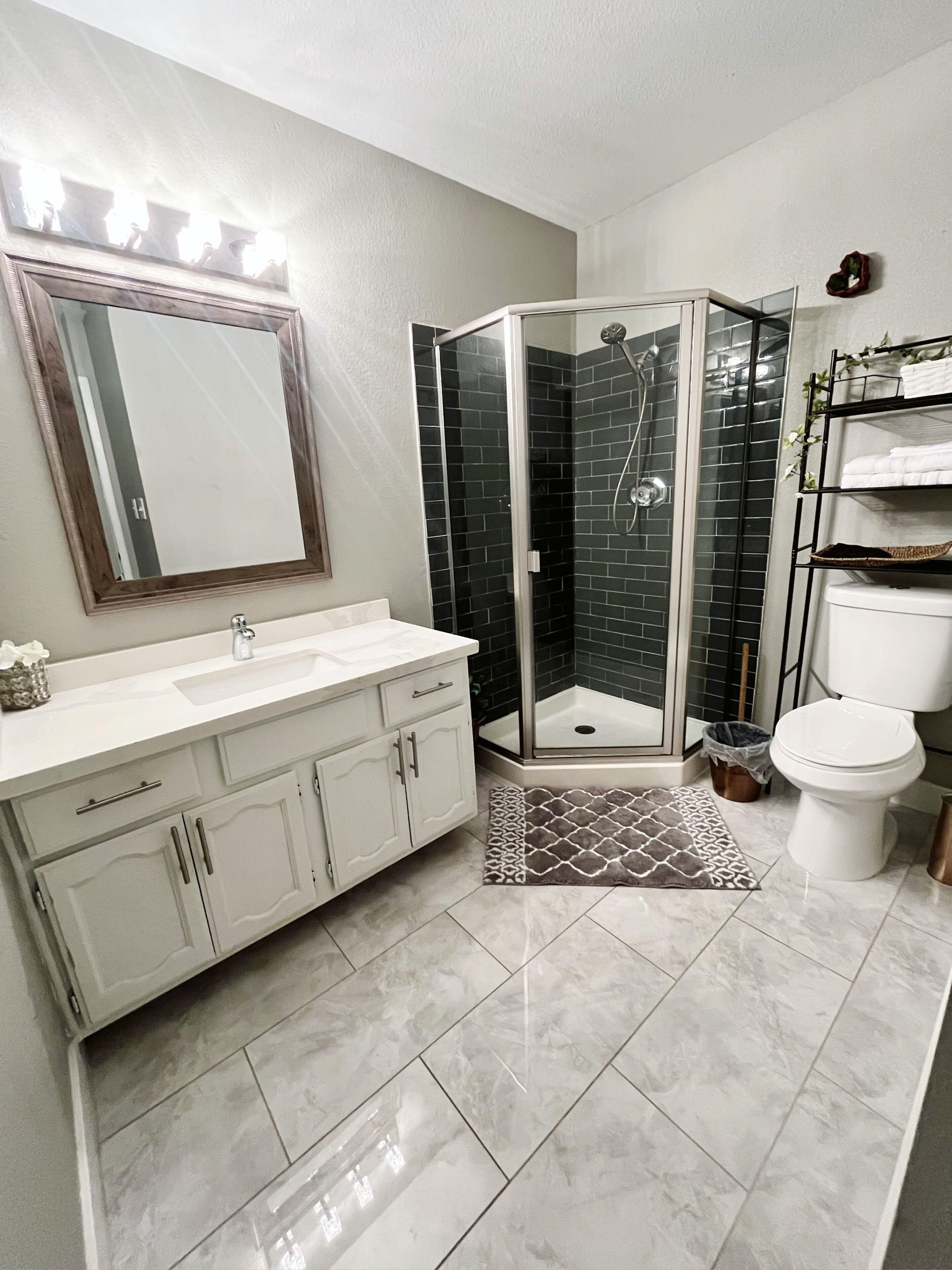 A bathroom with a white vanity, a glass shower enclosure, and a toilet.
