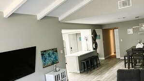 A modern living room with a flat-screen TV, a sofa, a coffee table, and a dining area with a bar. - Modern Zen Escape Near Strip, Downtown, Airport & Convention Center (Las Vegas)
