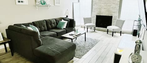 A modern living room with a sectional sofa, a fireplace, and a dining area.