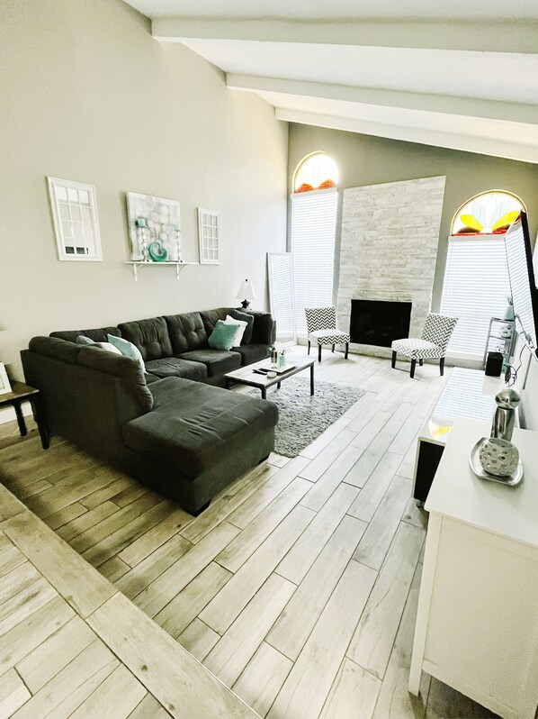 A modern living room with a sectional sofa, a fireplace, and a dining area.