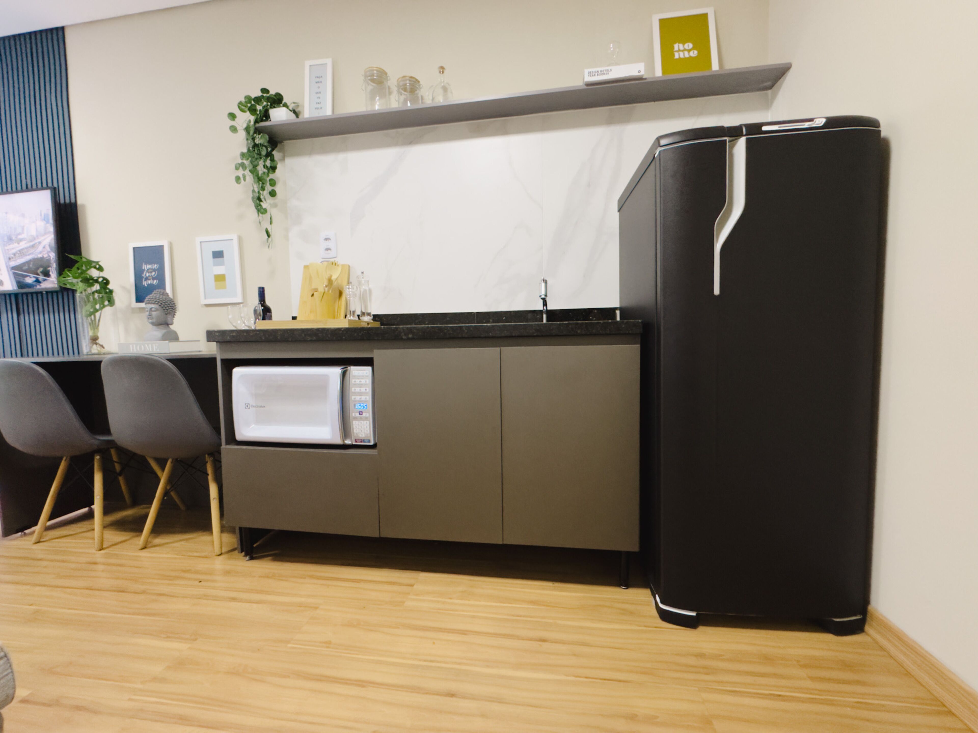 A compact kitchen with a built-in microwave, a black refrigerator, and a small countertop with a plant and decorative items.