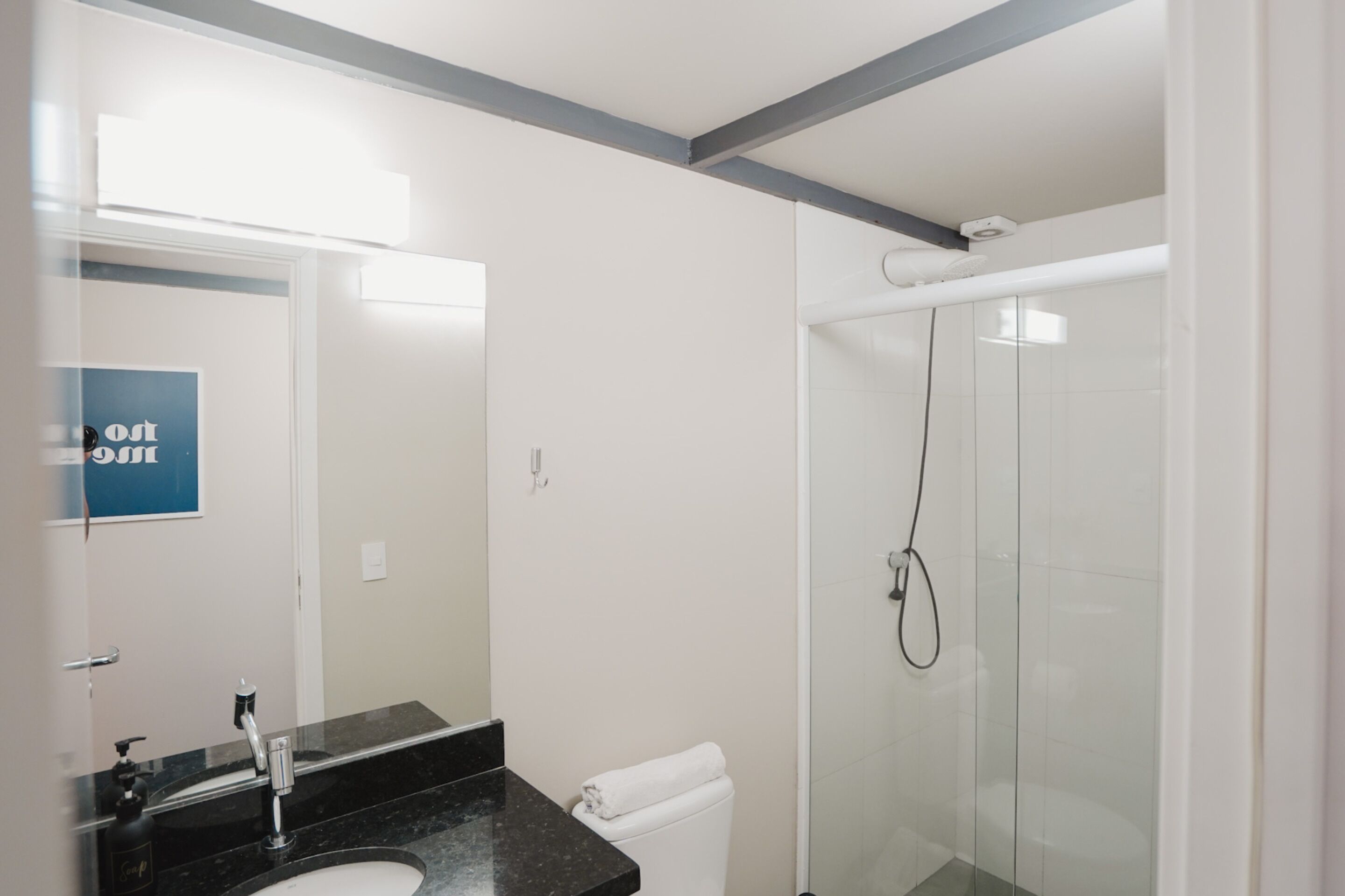 Un baño moderno con lavamanos de superficie negra, inodoro blanco y ducha con mampara de vidrio.