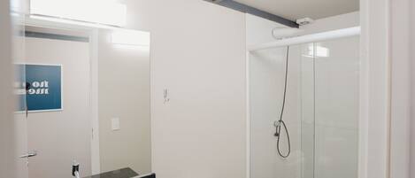 Un baño moderno con lavamanos de superficie negra, inodoro blanco y ducha con mampara de vidrio.