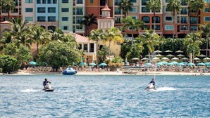 A hotel with colorful buildings, palm trees, and a beach.