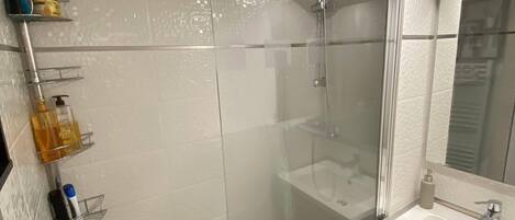 A modern bathroom with a glass-enclosed shower, a white sink, and a mirror above it.