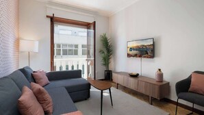 A modern living room with a grey sectional sofa, a wooden coffee table, and a TV mounted on the wall. - Prized Spacious Flat | Balcony by HostWise (Porto)