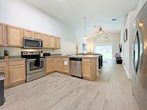 Modern kitchen with central island, stainless steel appliances, and a large window.