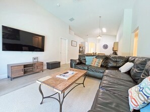 Relax in this stylish living room with a large flat-screen TV, comfortable leather sofa, and a coffee table for unwinding.