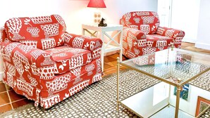A living room with two patterned sofas, a glass coffee table, a red lamp, and a painting of a cityscape. - Best Apt in Chevy Chase DC Big Sleeps 4-5, 4 blks to Metro (Washington)