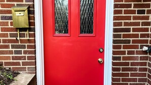 A red door with two glass panels, a mailbox, and a wall-mounted light fixture. - Best Apt in Chevy Chase DC Big Sleeps 4-5, 4 blks to Metro (Washington)