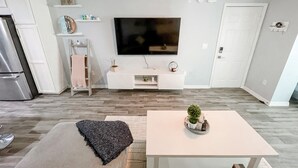 Een moderne keuken met een geïntegreerde koelkast, een flatscreen televisie en een eethoek met een tafel en stoelen.