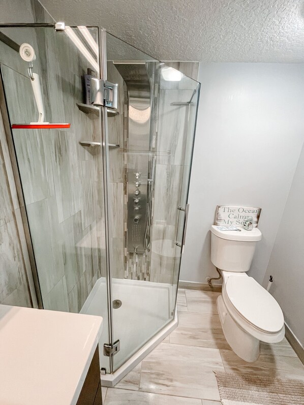 A modern bathroom with a glass-enclosed shower, a toilet, and a white sink.
