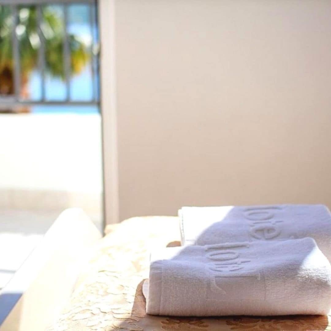 Une serviette blanche, soigneusement pliée, est posée sur un lit recouvert d’une couvre-lit à motifs floraux.