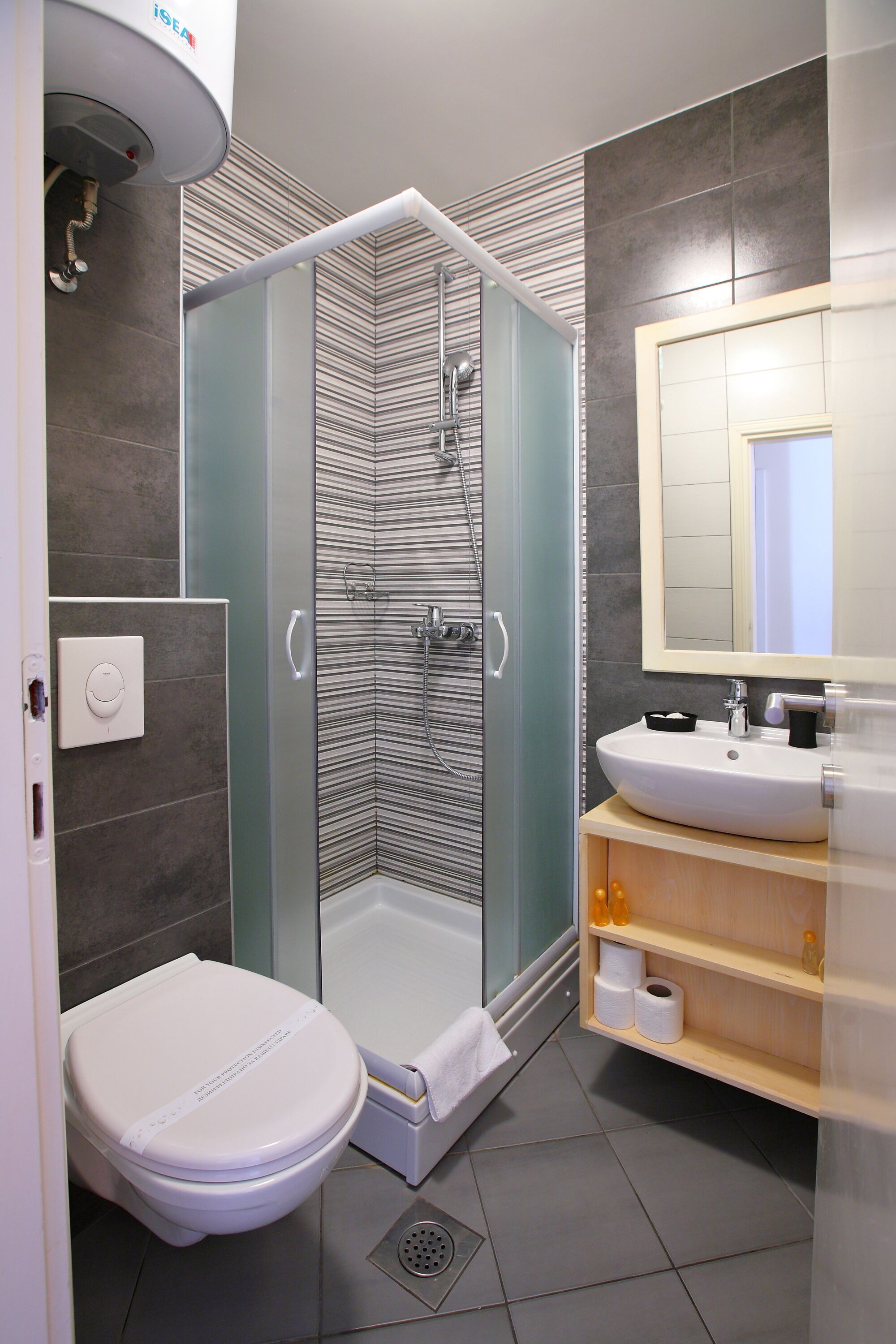 A modern bathroom with a glass-enclosed shower, a white toilet, and a sink with a mirror above it.