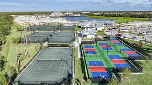 Ein Tennisplatzkomplex mit mehreren Plätzen, einem Parkplatz und Wohnhäusern im Hintergrund.