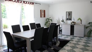 Un comedor con una mesa, sillas, un armario y una ventana con cortinas.