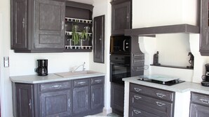 Una cocina con armarios de madera oscura, microondas, horno y cafetera.