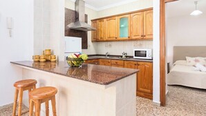 Eine Küche mit Granit Arbeitsplatten, Holzschränken, einer eingebauten Mikrowelle und einer Kochinsel mit Sitzgelegenheiten.