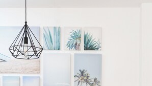 A room with a green sofa, a white high chair, and a wall with various framed artworks. - Home2Book Stunning Apartment Candelaria, Terrace (Las Caletillas)
