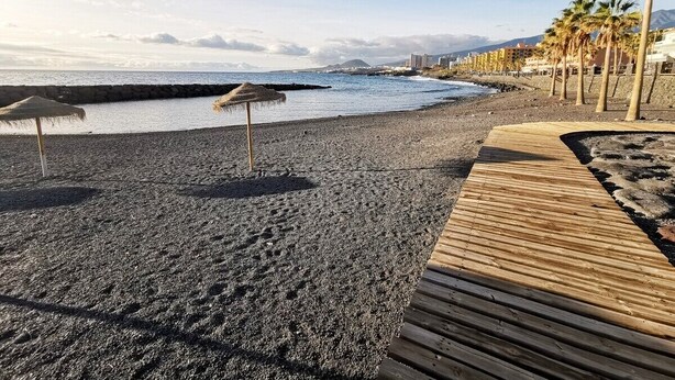 A beach with a wooden walkway, palm trees, and a rocky shoreline. - Home2Book Stunning Apartment Candelaria, Terrace (Las Caletillas)