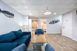 A modern living room with a blue sofa, a wooden coffee table, and a hanging light fixture.