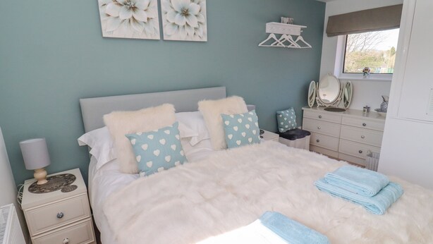 A bedroom with a bed, nightstands, a dresser, a mirror, and artwork on the wall. - Robellen Corner (Banbury)