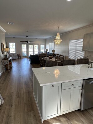 A spacious kitchen with a large island, wooden flooring, and a ceiling fan.
