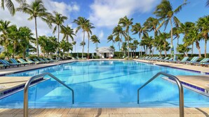Une piscine avec des chaises longues et des palmiers.