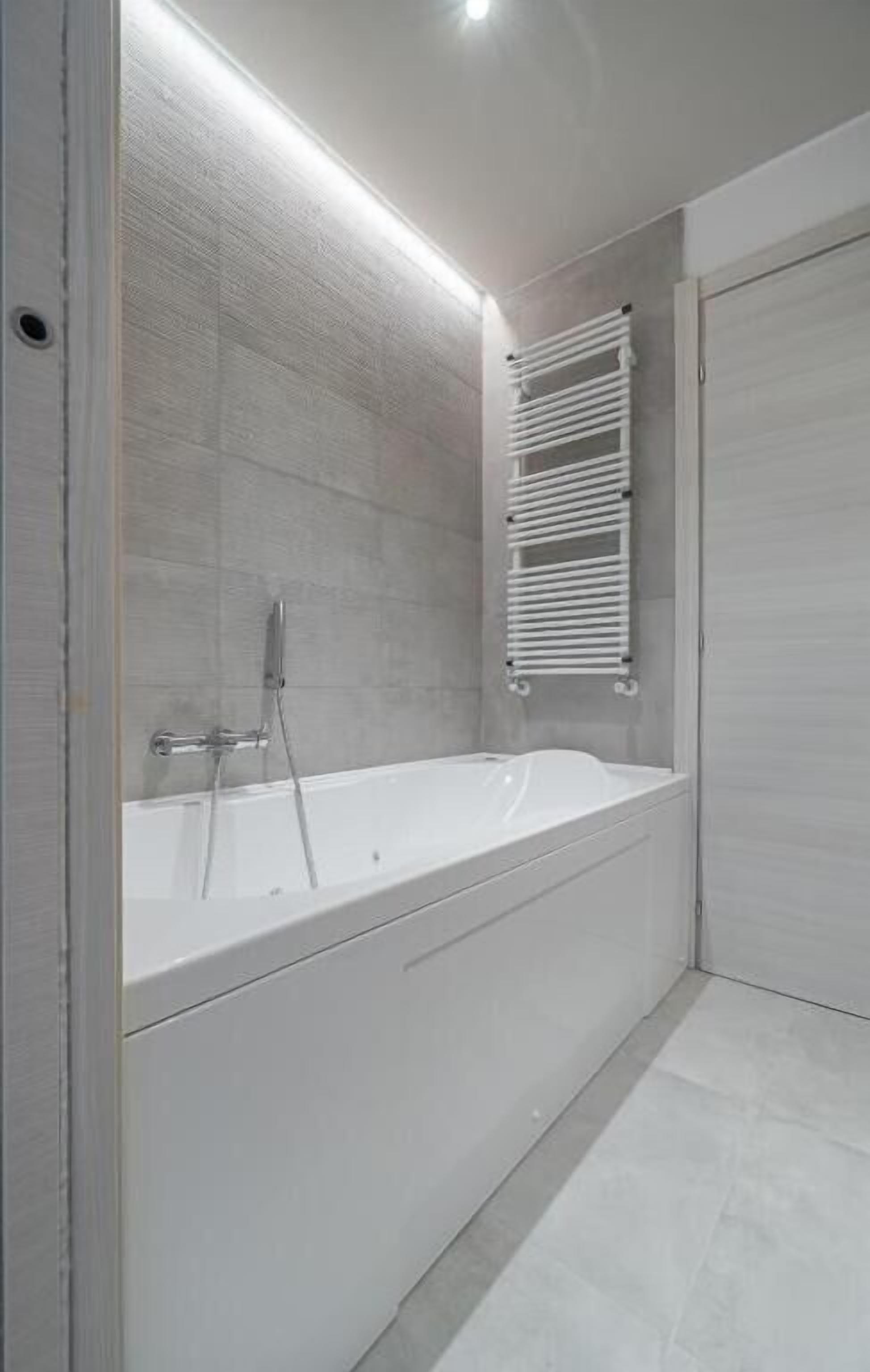 Un baño moderno con una bañera independiente, un perchero y una puerta cerrada.