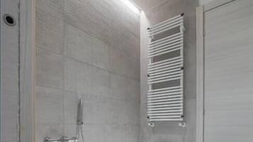 Un baño moderno con una bañera independiente, un perchero y una puerta cerrada.