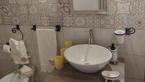 A bathroom with a white sink, a mirror, a toilet, and patterned tiles. - Casedda Ostunese (Ostuni)