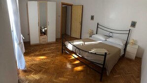 Een slaapkamer met een bed, nachtkastjes, een kledingkast en een spiegel.